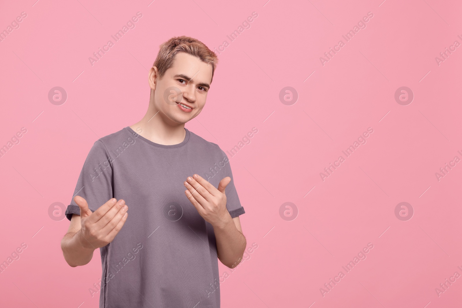 Photo of Happy man inviting to come in against pink background, space for text