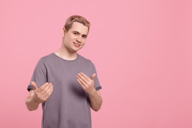 Photo of Happy man inviting to come in against pink background, space for text