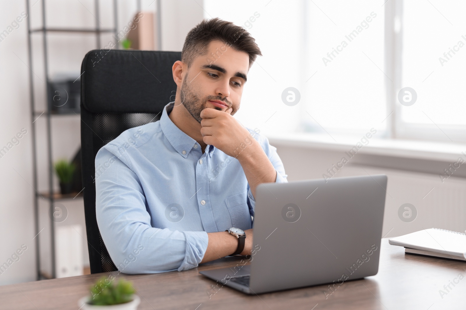 Photo of Young programmer working with laptop in office