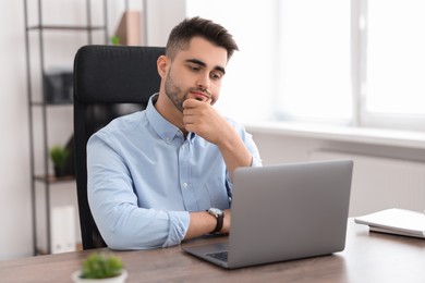 Young programmer working with laptop in office