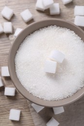 Different types of white sugar in bowl on wooden table, top view