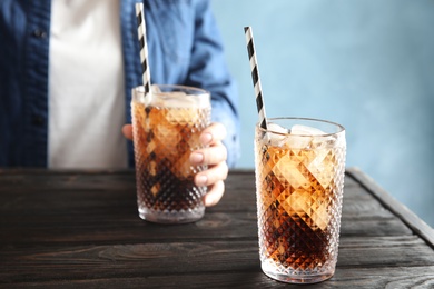 Photo of Glass of tasty refreshing cola and blurred woman on background