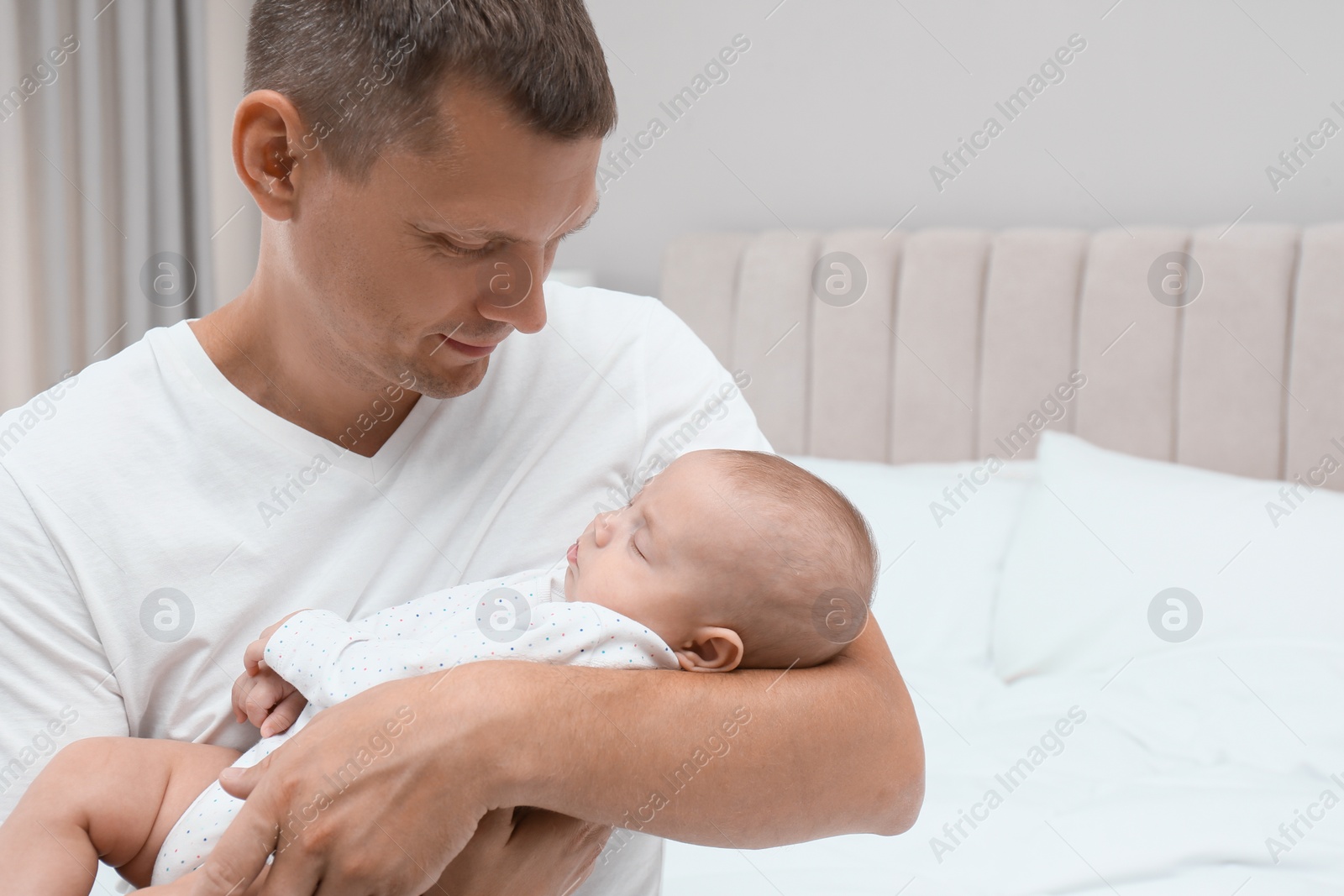 Photo of Happy father holding his cute sleeping baby at home