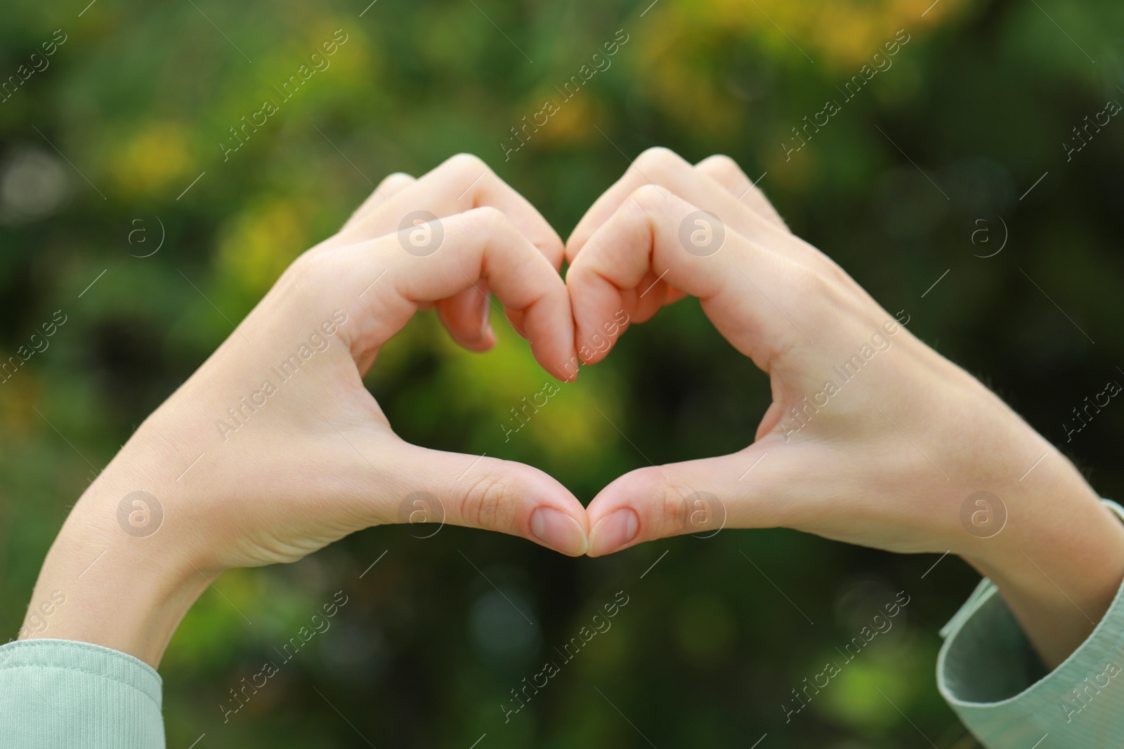 Photo of Woman making heart with hands outdoors, closeup