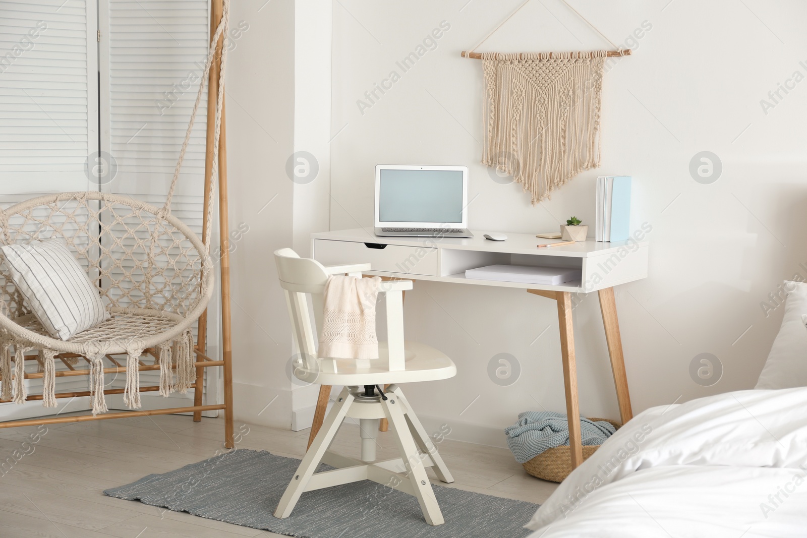 Photo of Stylish room interior with workplace and hanging chair