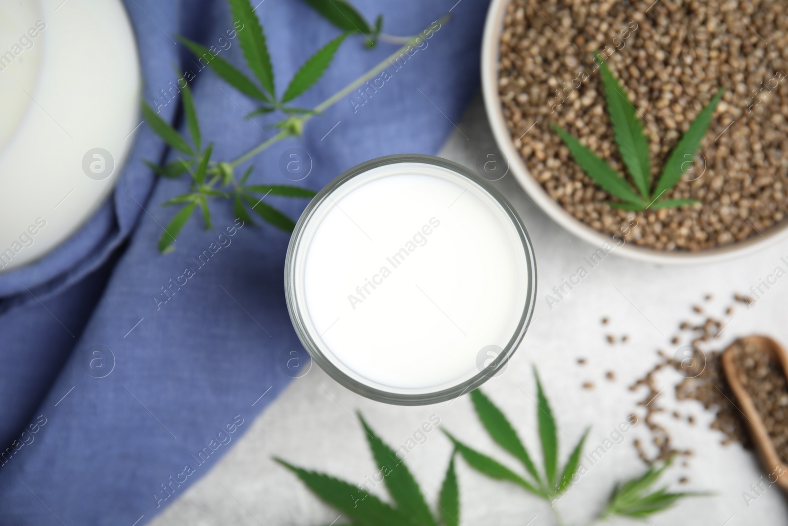 Photo of Hemp milk and seeds with fresh leaves on light grey table, flat lay