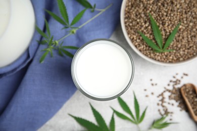 Photo of Hemp milk and seeds with fresh leaves on light grey table, flat lay
