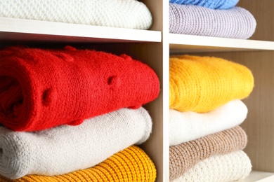 Photo of Folded colorful winter sweaters on shelves as background