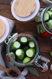 Glass jars with fresh cucumbers and other ingredients on wooden table, flat lay. Canning vegetables