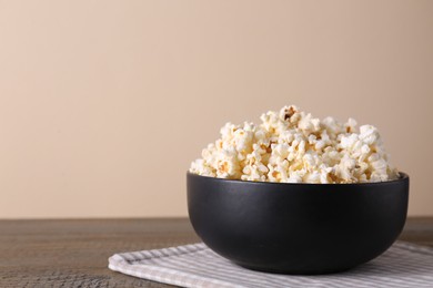 Delicious popcorn in bowl on wooden table. Space for text