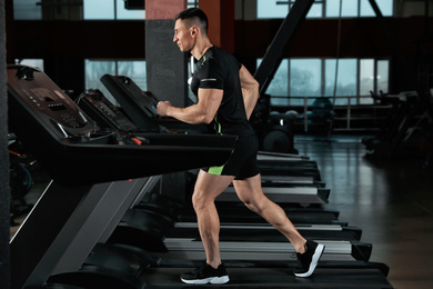 Photo of Man working out on treadmill in modern gym
