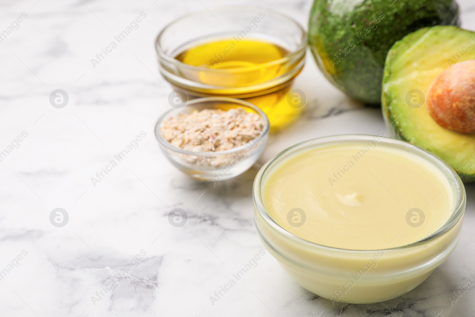 Photo of Handmade face mask in glass bowl and ingredients on marble table