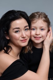 Beautiful mother with little daughter on grey background