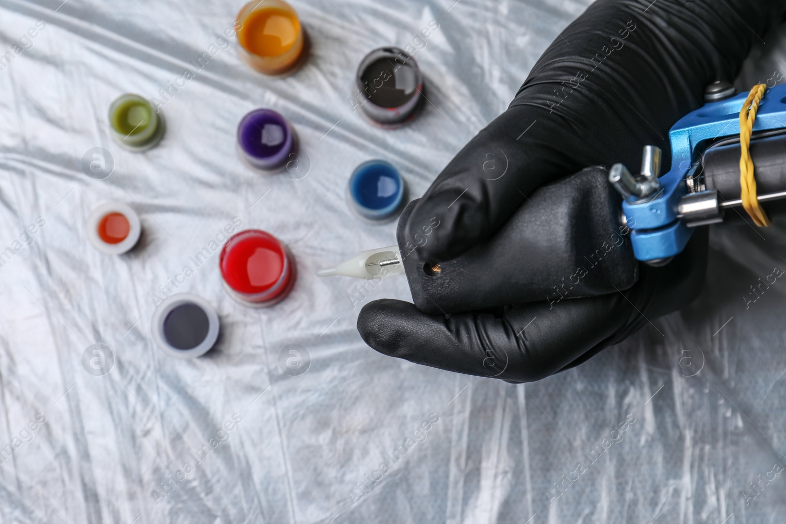 Photo of Tattoo artist with machine and inks at table, top view