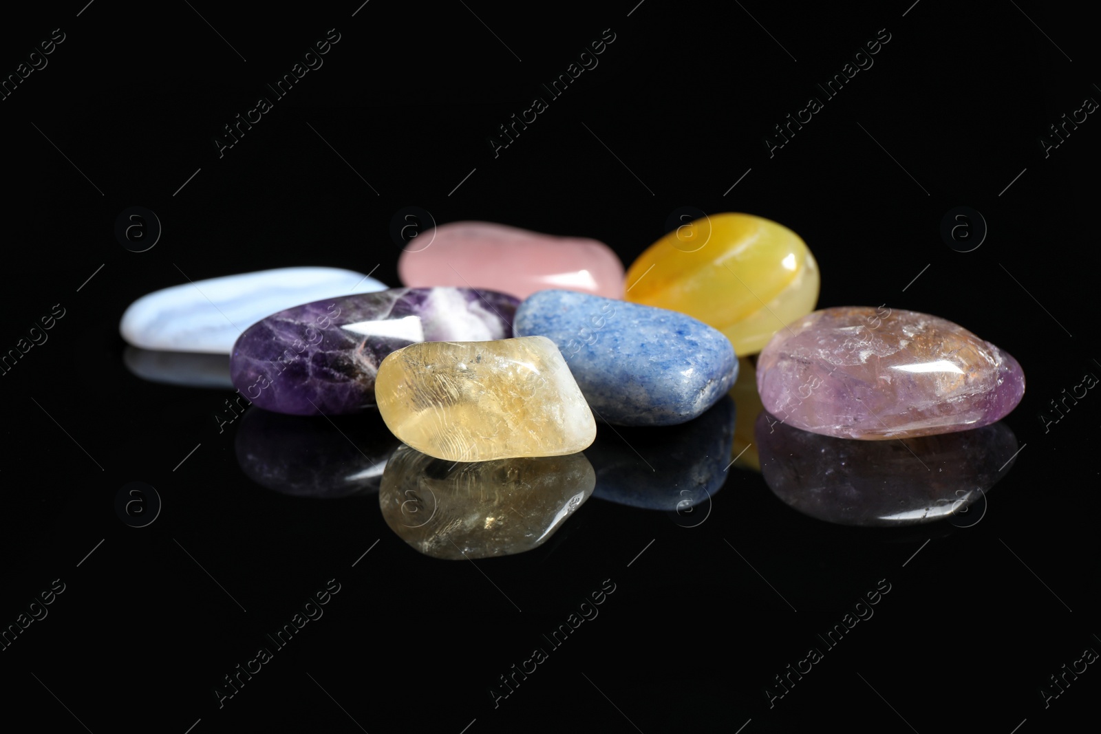 Photo of Pile of different beautiful gemstones on black background