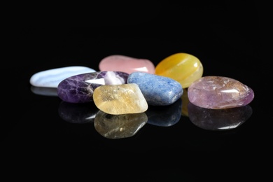 Pile of different beautiful gemstones on black background
