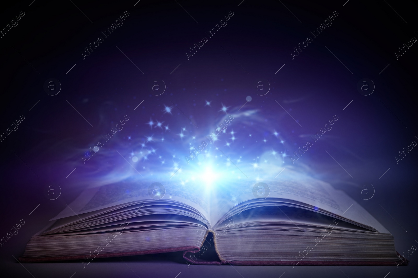 Image of Open book with magic glowing on table. Fairy tale