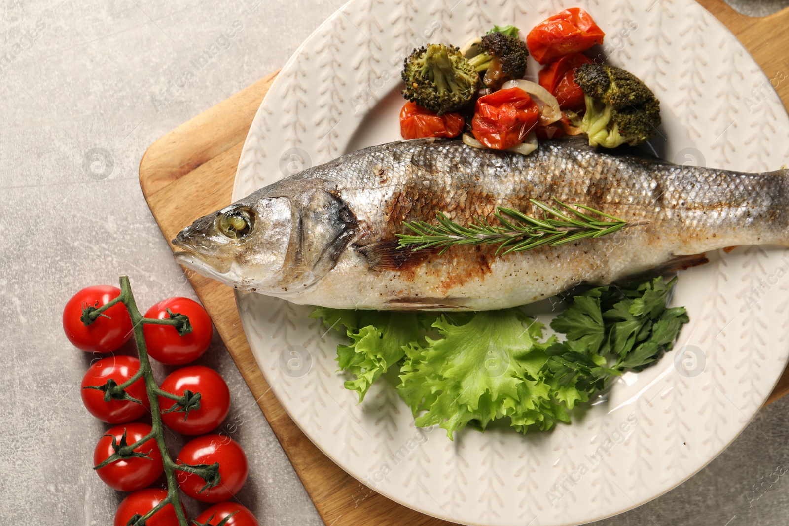 Photo of Delicious baked fish and vegetables on light grey table, top view