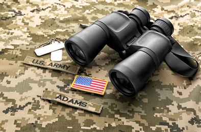 Photo of Military ID tags, patches and binocular on camouflage background