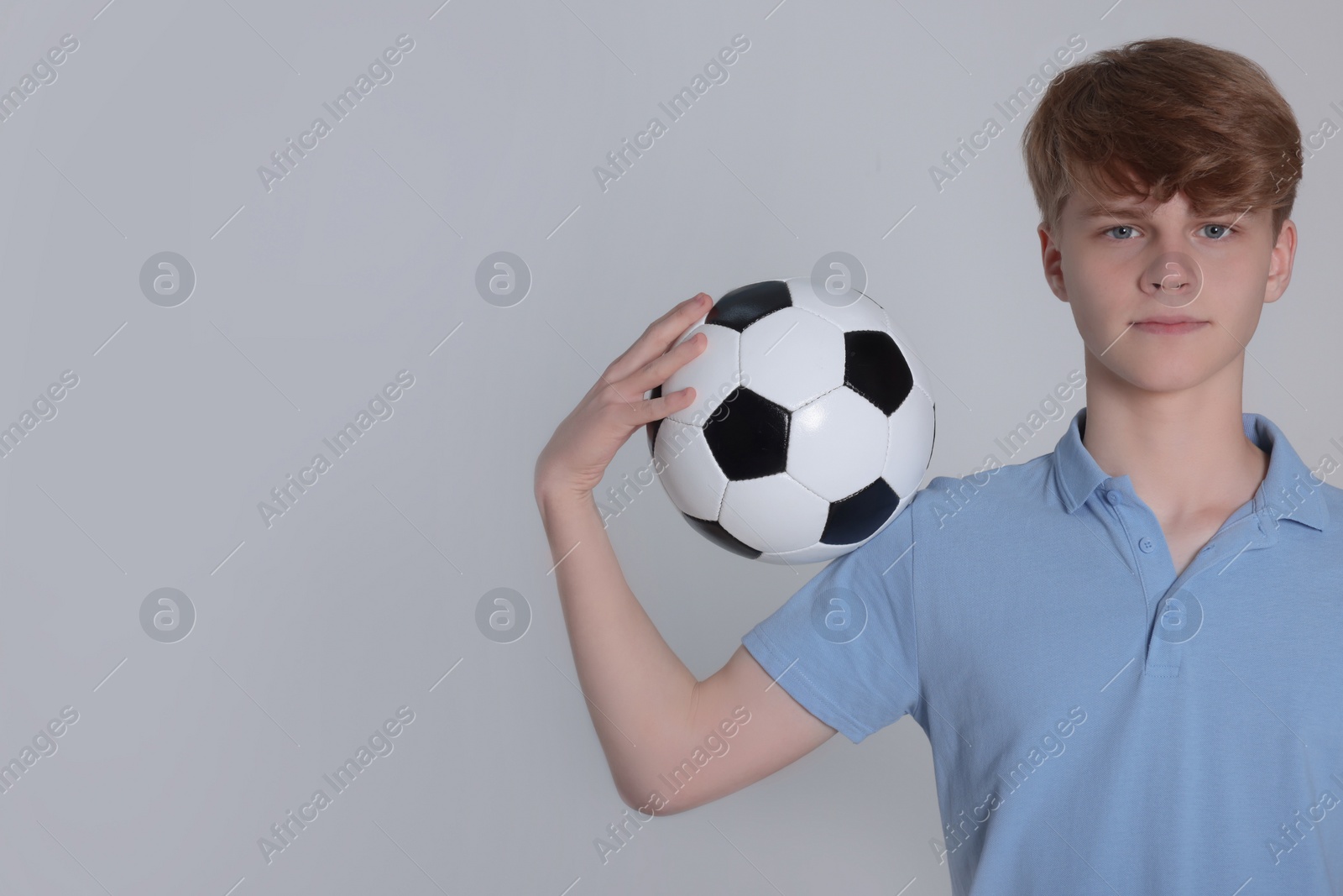 Photo of Teenage boy with soccer ball on light grey background. Space for text