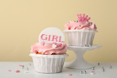 Photo of Delicious cupcakes with pink cream and toppers for baby shower on white table