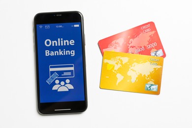 Photo of Smartphone with online banking app and credit cards on white background, flat lay