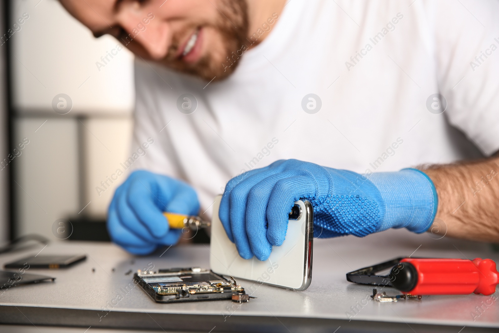 Photo of Technician repairing mobile phone at table in workshop, closeup