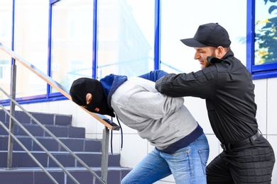 Police officer arresting masked criminal outdoors