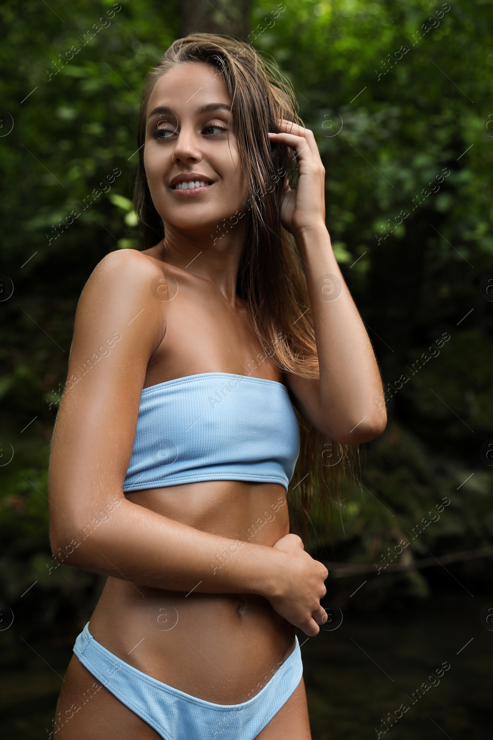 Photo of Beautiful young woman in light blue bikini near mountain river outdoors