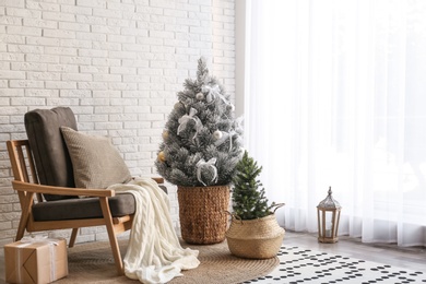 Photo of Stylish interior with beautiful Christmas tree near white brick wall. Space for text