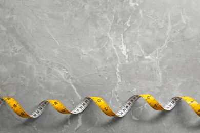 Photo of Measuring tape on light grey marble table, top view. Space for text