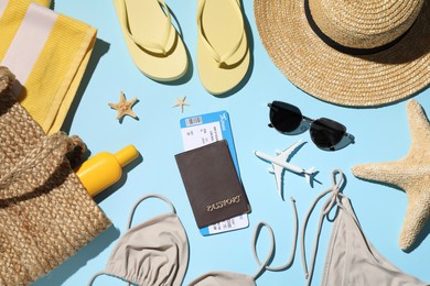 Flat lay composition with passport, tickets and beach accessories on light blue background. Time to travel