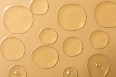 Photo of Drops of hydrophilic oil on beige background, flat lay