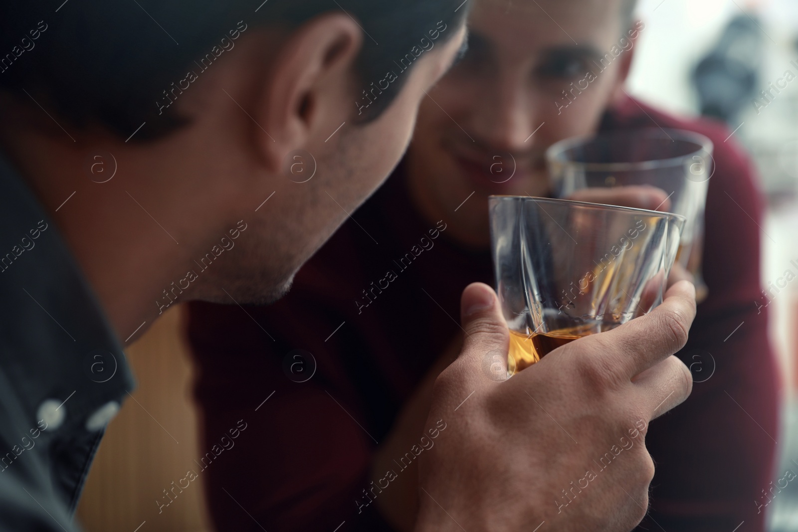 Photo of Young men drinking whiskey together in bar
