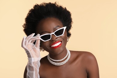 Photo of Fashionable portrait of beautiful happy woman with stylish sunglasses on beige background