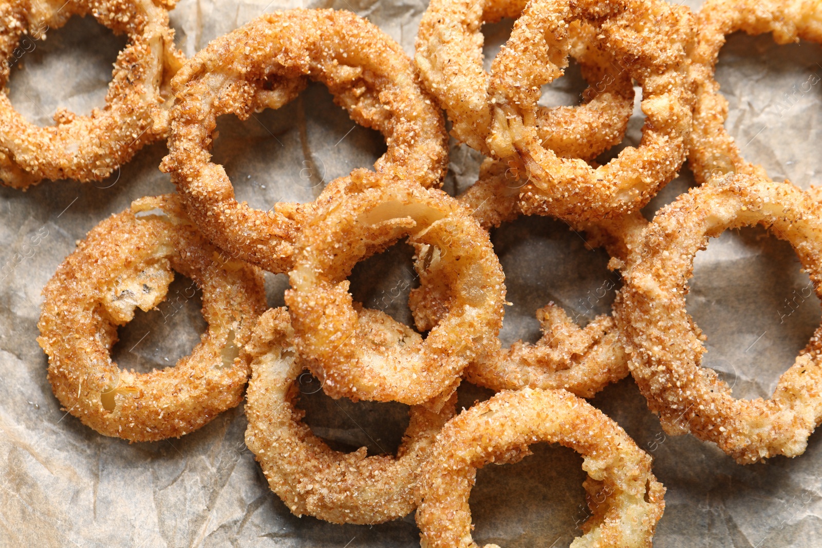 Photo of Parchment paper with homemade crunchy fried onion rings, top view
