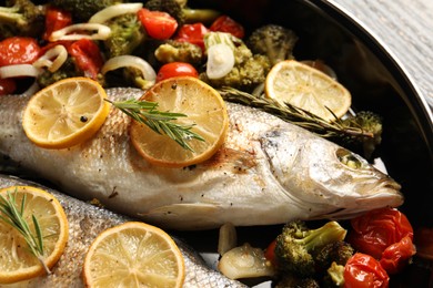 Photo of Baked fish with vegetables, rosemary and lemon on table, closeup