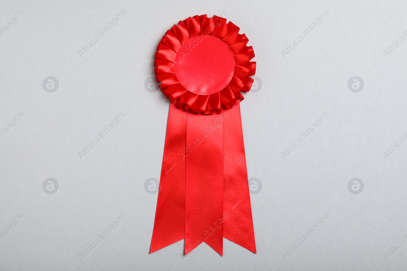 Photo of Red award ribbon on grey background, top view