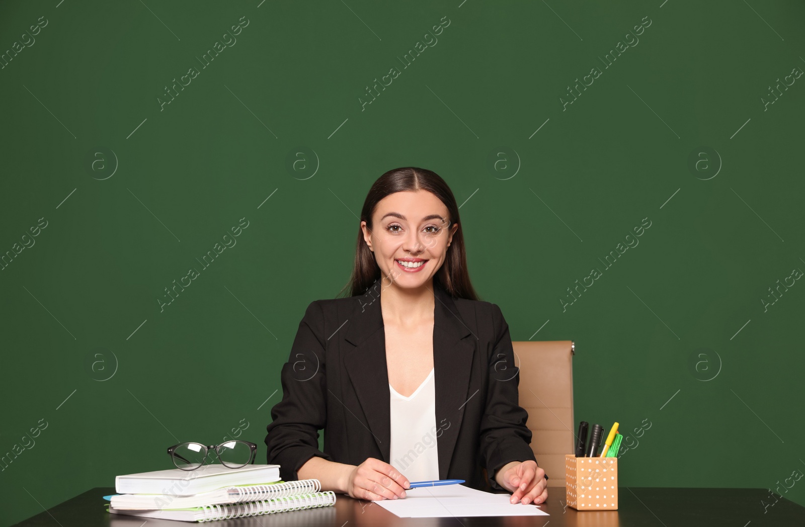 Photo of Portrait of young teacher at table against green background