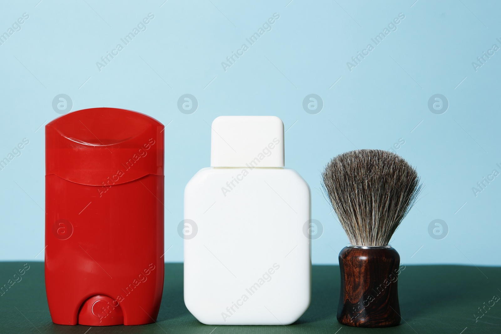 Photo of Shaving brush, lotion and deodorant for men on table against color background