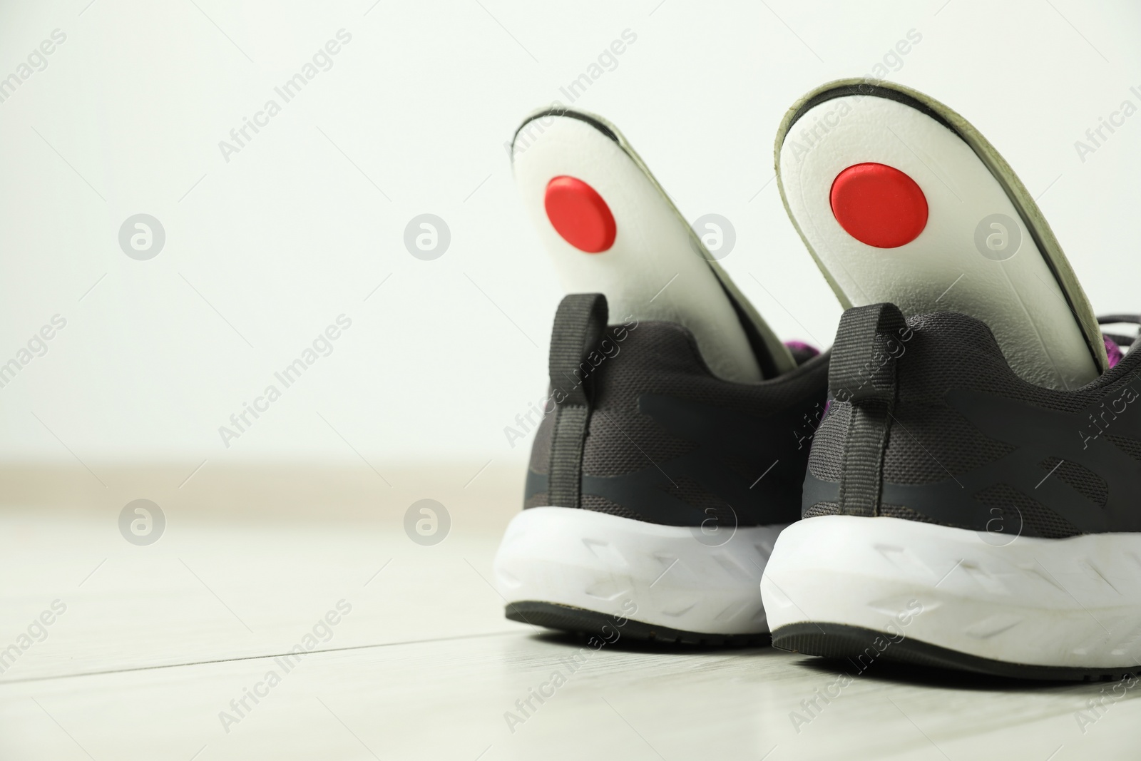 Photo of Orthopedic insoles in shoes on floor, closeup. Space for text