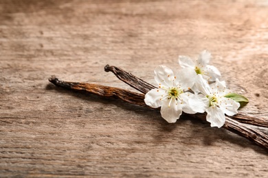 Vanilla sticks and flowers on wooden background