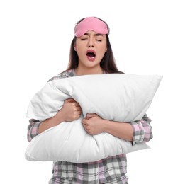 Photo of Tired young woman with sleep mask and pillow yawning on white background. Insomnia problem