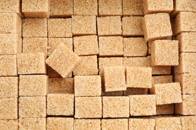 Brown sugar cubes as background, top view