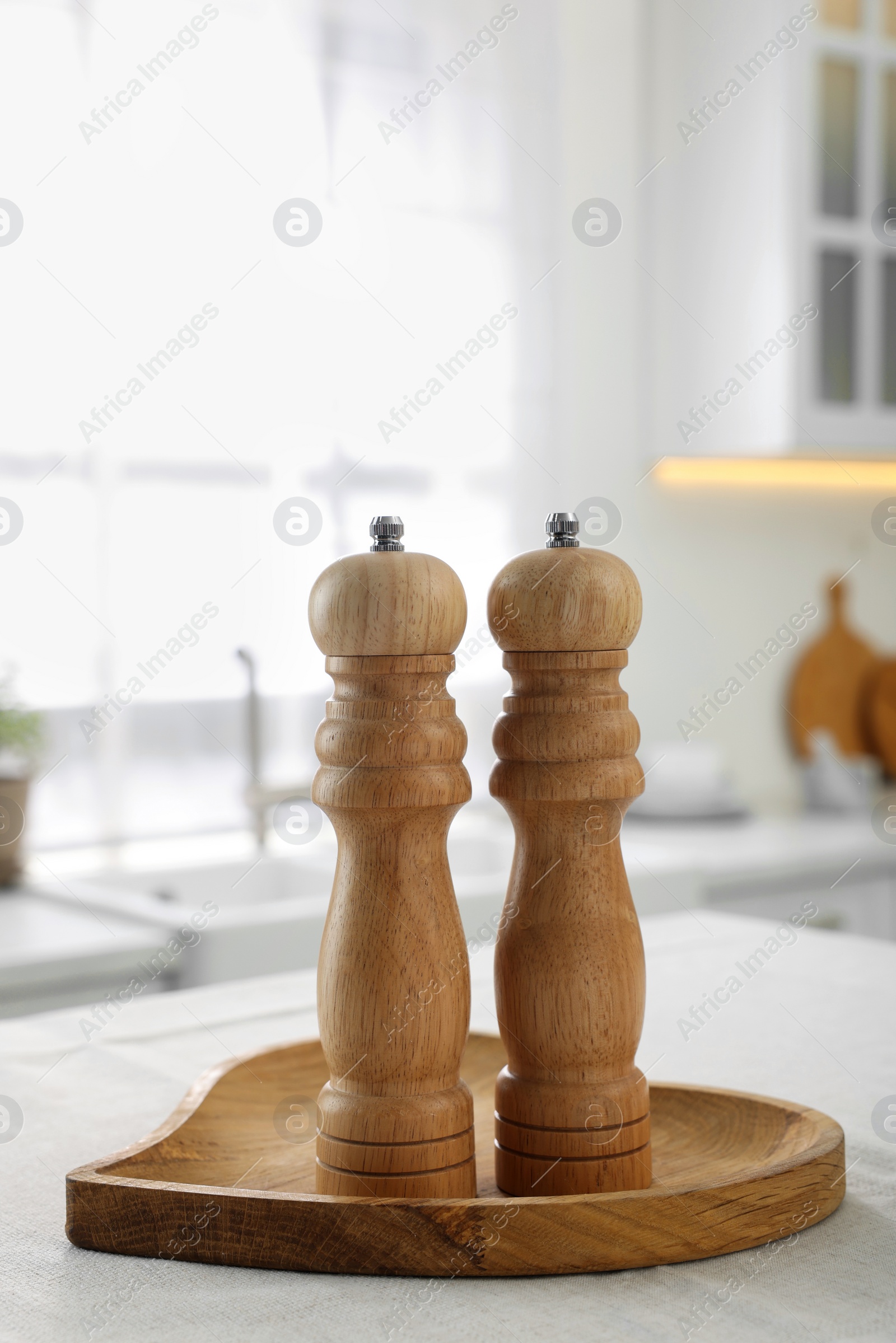 Photo of Wooden salt and pepper shakers on white table in kitchen