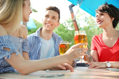 Photo of Young people with glasses of cold beer at table