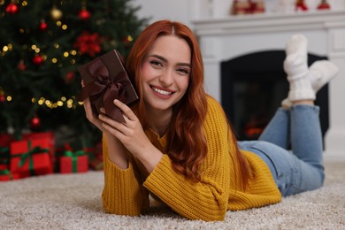 Photo of Happy young woman with Christmas gift at home