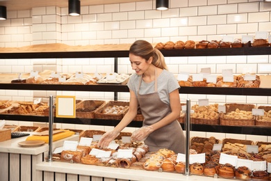 Beautiful woman near showcase with pastries in bakery shop