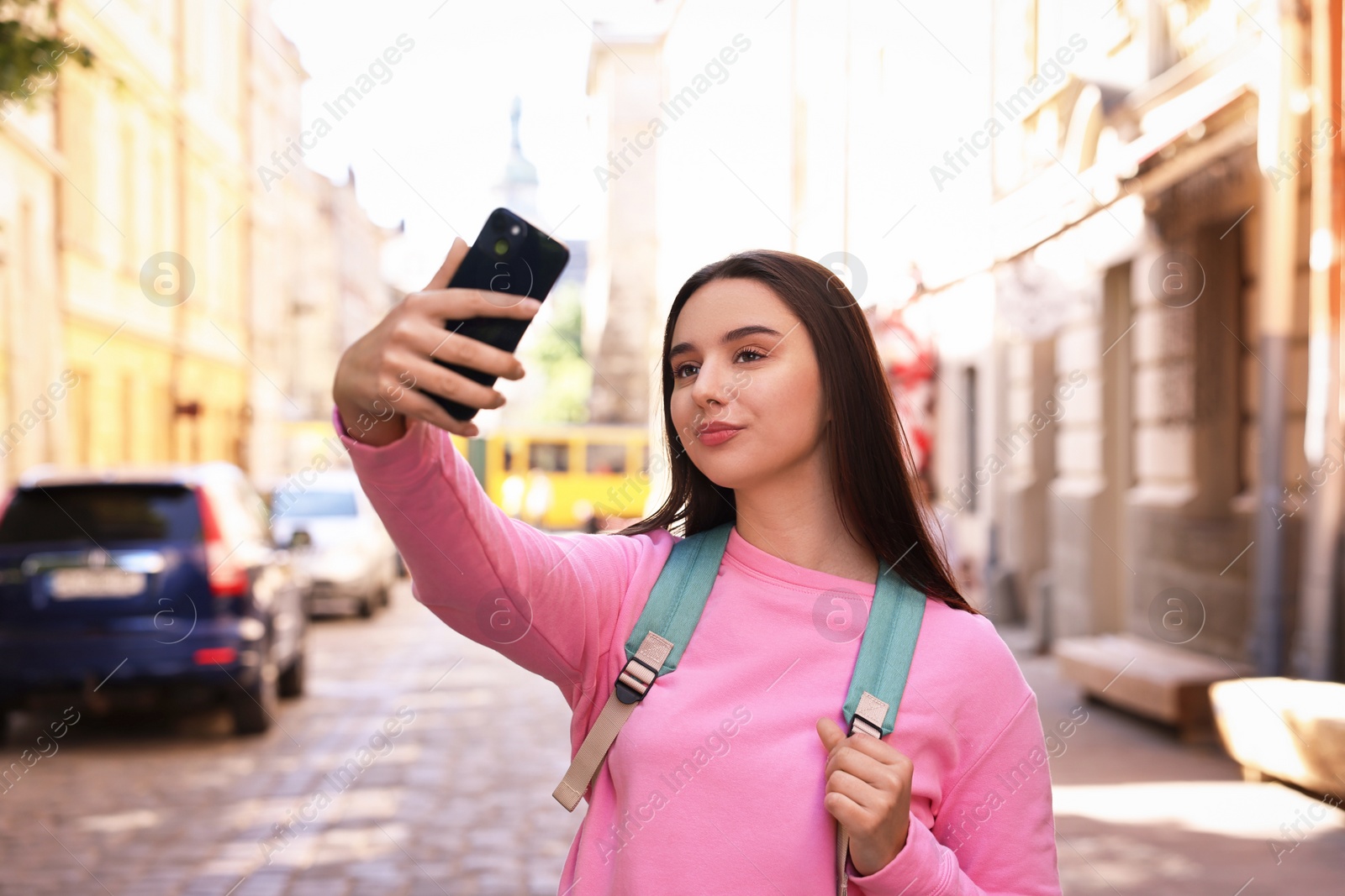 Photo of Travel blogger takIng selfie with smartphone on city street
