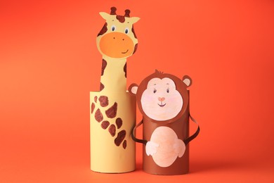 Photo of Toy monkey and giraffe made from toilet paper hubs on orange background. Children's handmade ideas